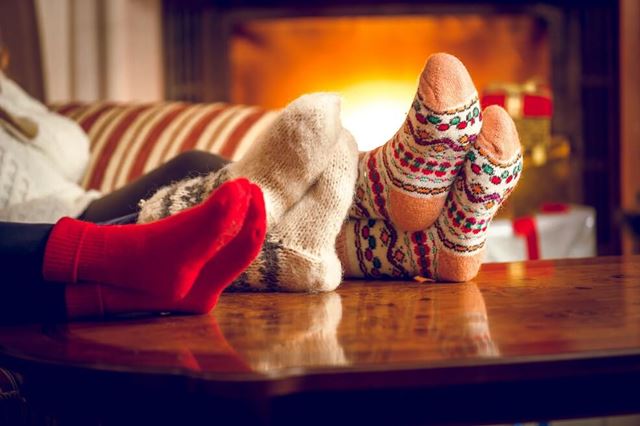 Feet with festive socks on up on a table in front of a fireplace